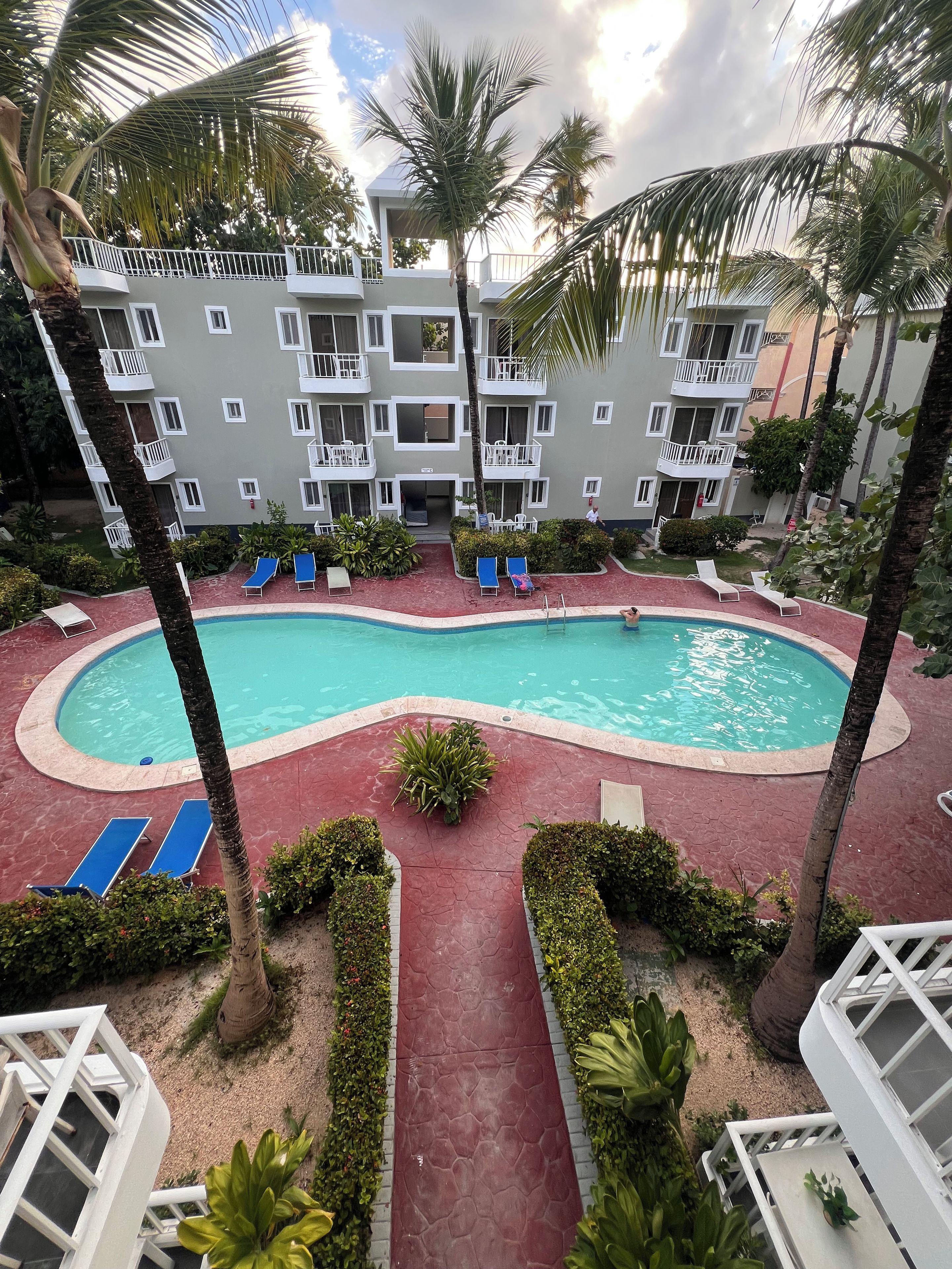 Um hotel com piscina, espreguiçadeiras e palmeiras.