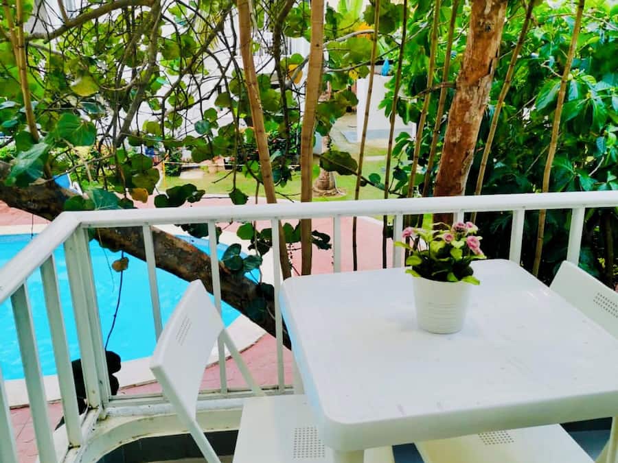Un área de estar al aire libre con mesa y sillas, una planta en maceta y vista a una piscina.