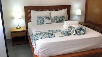 Una cama bien hecha con ropa de cama estampada, un cabecero de madera y lámparas de noche.