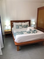 A neatly made bed with patterned bedding, a wooden headboard, and bedside lamps.