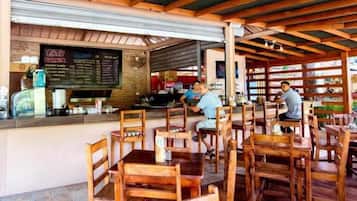 Un restaurante con mesas y sillas de madera, una barra con un menú y una pared de ladrillo.