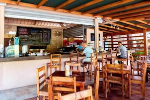 A restaurant with wooden tables and chairs, a counter with a menu, and a brick wall.