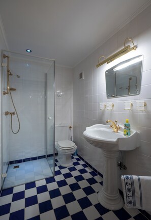 Ein Badezimmer mit einem Schachbrettmuster auf dem Boden, einem weißen Waschbecken, einer Toilette und einer gläsernen Duschkabine.