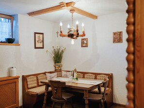 Ein Essbereich mit Holztisch und Stühlen, einer Kronleuchter und Wandbildern.