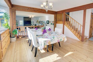Un comedor con una mesa de madera para cuatro personas, una lámpara de araña y una escalera.