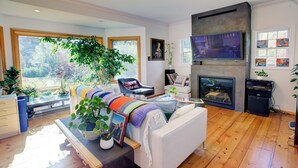 Amplia sala de estar con chimenea, un sofá y un ventanal con vistas a un jardín.