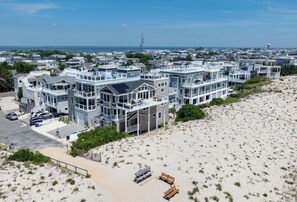 Une propriété située en bord de mer, comprenant plusieurs bâtiments à étages, une plage de sable et une vue dégagée sur l’océan.
