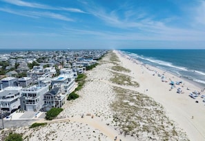 Un quartier résidentiel situé sur la côte, avec des propriétés donnant sur la plage et une plage de sable.