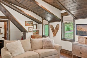 Come bedtime, this roomy loft sofa unfolds into a queen bed for two extra sleepers. By day, fuzzy pillows, a little gallery of framed landscapes, and a painted chest topped with a woven basket make the upstairs lounge feel lived-in and welcoming. - Bear Cub Lodge Gated 3BR Eagles Nest Lodge with Hot Tub, Sleeps 10 (Banner Elk)