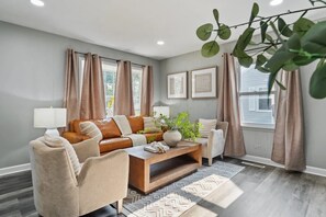 A living room with a brown leather sofa, beige armchairs, a wooden coffee table, and a patterned rug. - Charming and inviting 3 bedroom - 1 bathroom home in Streamwood (Streamwood)