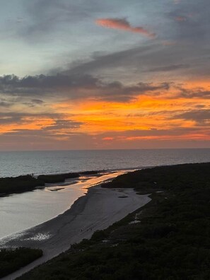A coastal landscape with a beach, a water channel, and a path leading to the beach. - Sunsets at 19 Beachfront Penthouse Condo (Marco Island)