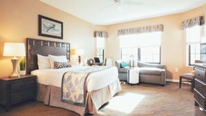 Une chambre d’hôtel avec un grand lit, un bureau, une chaise et une commode.