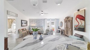 A spacious living room with a marble coffee table, a ceiling fan, and a large painting of a flamingo. - Elegant & Cozy 3-Bedroom Home in Ocala – Perfect for a Relaxing Stay (Ocala)