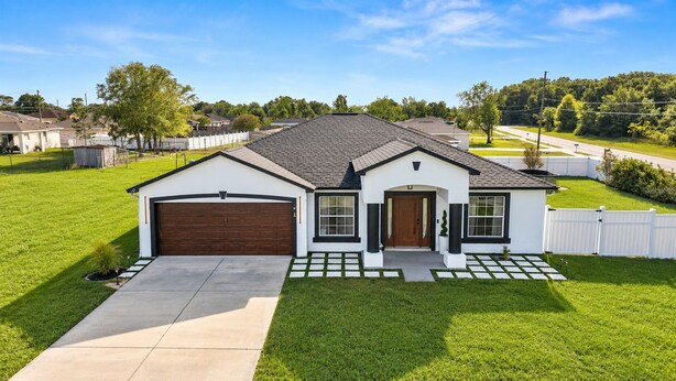 A single-story house with a garage, a front porch, and a well-maintained lawn. - Elegant & Cozy 3-Bedroom Home in Ocala – Perfect for a Relaxing Stay (Ocala)