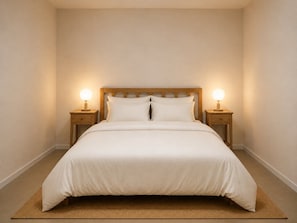 A neatly made bed with a wooden headboard, two bedside tables with lamps, and a plain wall. - 1-bed Apartment Near Darwin Waterfront (Darwin)