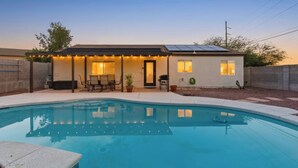 A residential property with a swimming pool, a covered patio with seating, and a solar panel roof. - Remodeled 3BR Home With Private Pool Near Northwest Medical Center And I-10 (Tucson)
