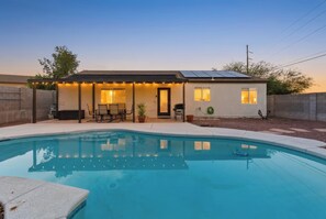 Una propietat residencial amb piscina, un porxo cobert amb seients i un teulat amb panells solars.