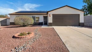 A single-story house with a garage, solar panels, and a landscaped front yard with rocks and plants. - Remodeled 3BR Home With Private Pool Near Northwest Medical Center And I-10 (Tucson)