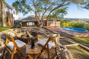 Quintal com lareira, área de estar externa, piscina e vista da paisagem ao redor.