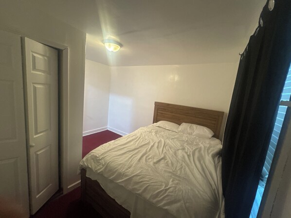 A bedroom with a single bed, a door, and a ceiling light.