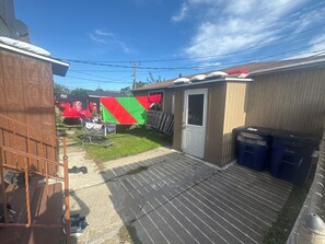 A residential backyard with a small shed, a clothesline, and a metal cart with items.