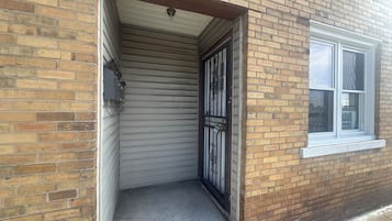 Un edificio de ladrillo con una puerta de garaje cerrada, una ventana con un letrero y un pequeño escalón de concreto que lleva a la puerta.