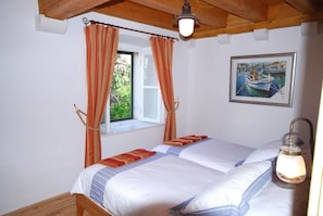 Un dormitorio con cama, cortinas, ventana, un cuadro y una lámpara.