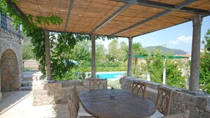 Un espacio de estar techado al aire libre con una piscina al fondo.