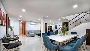 Uma sala de estar moderna com um sofá, uma mesa de jantar com cadeiras e uma escada.
