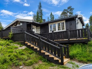 A two-story wooden cabin with a staircase leading to a deck. - Trysilfjell Ski in Ski out Family Cabin (Trysil)