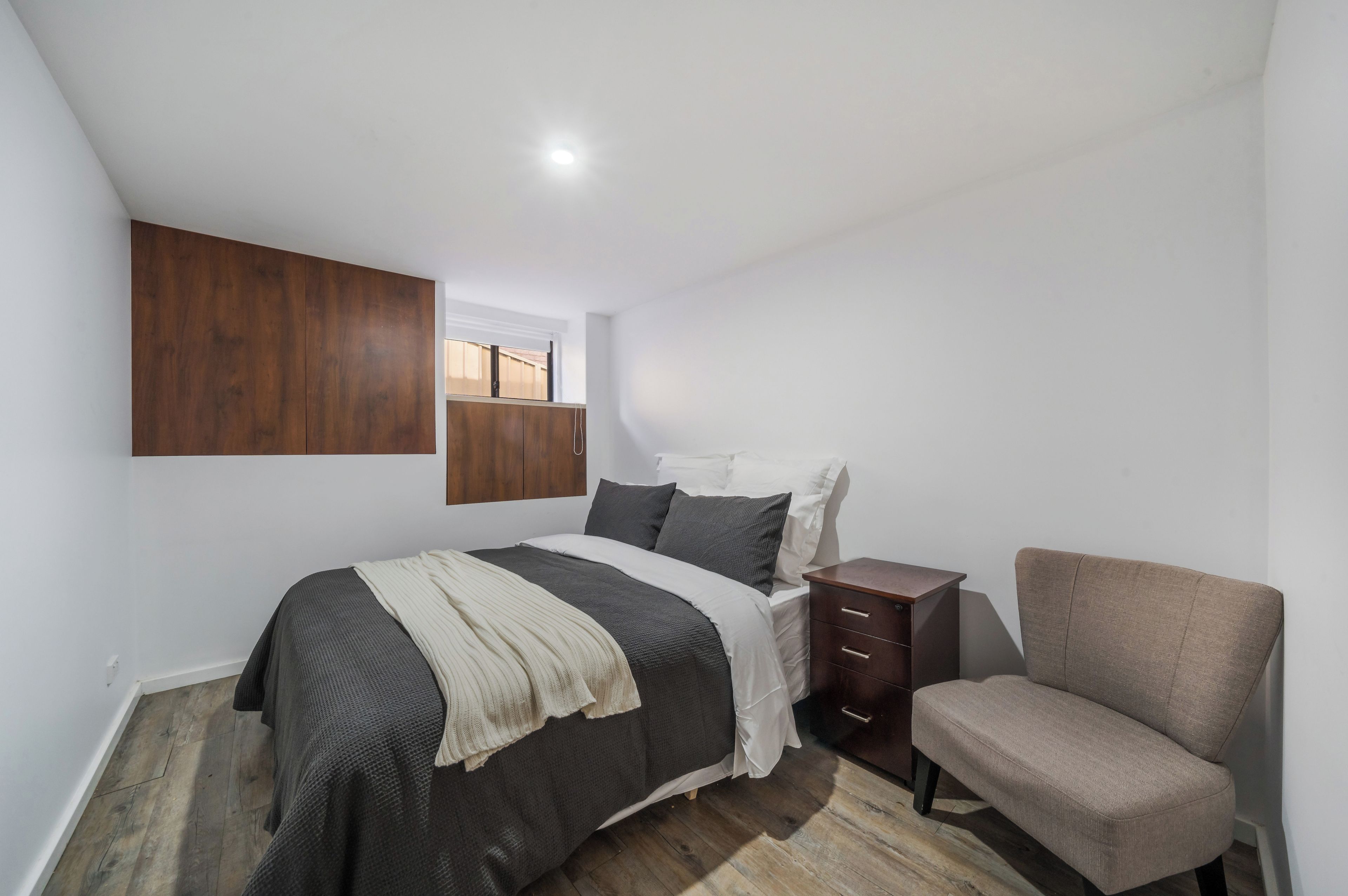 A bedroom with a bed, a nightstand, a chair, and a wardrobe.