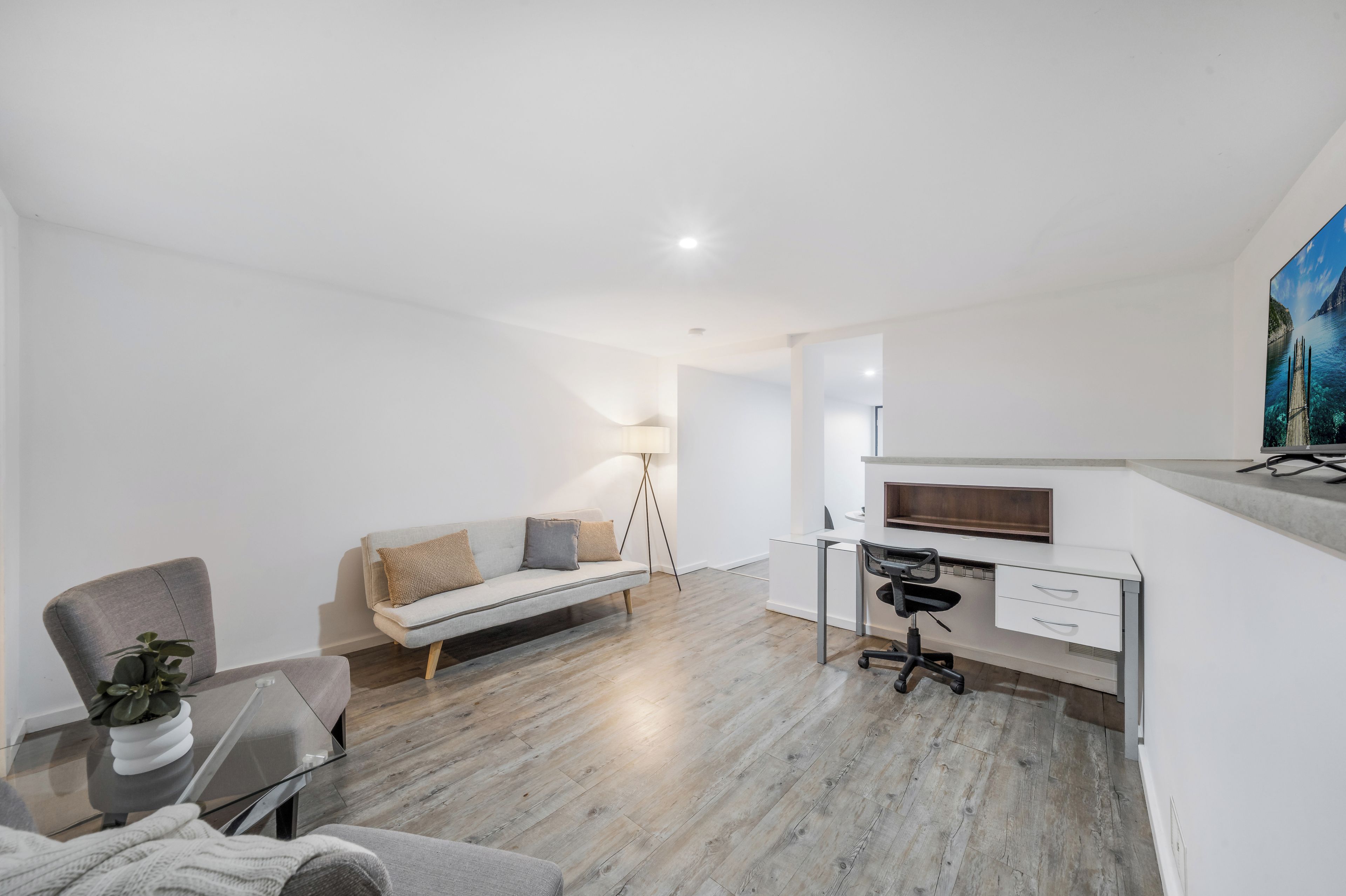 A modern, minimalist room with a sofa, a desk, and a chair.