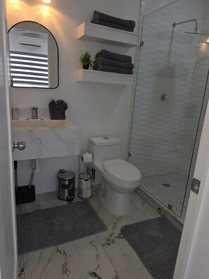 Casa de banho moderna com sanita, lavatório e chuveiro.