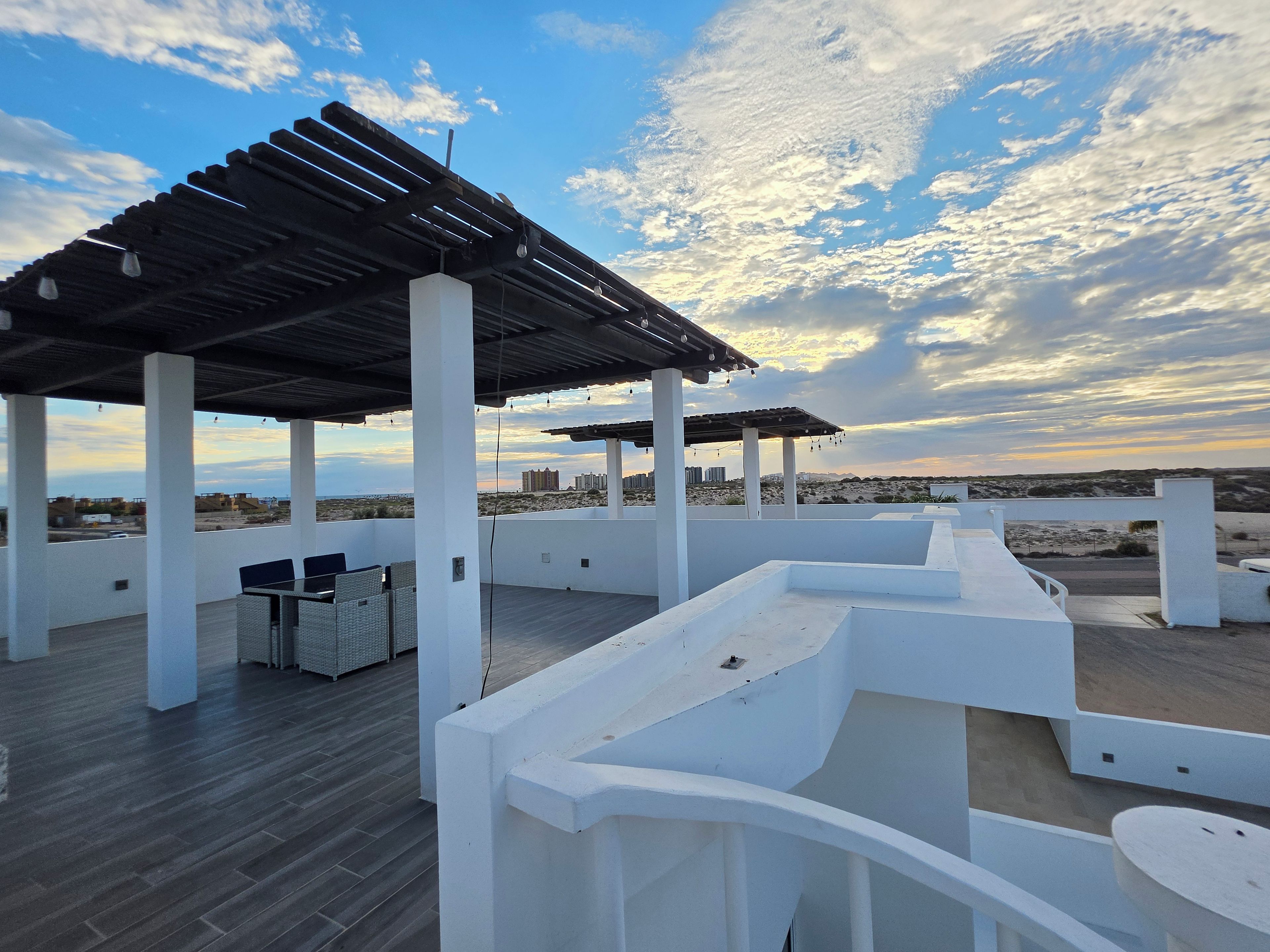 An outdoor terrace with a pergola, seating area, and a view of the cityscape.