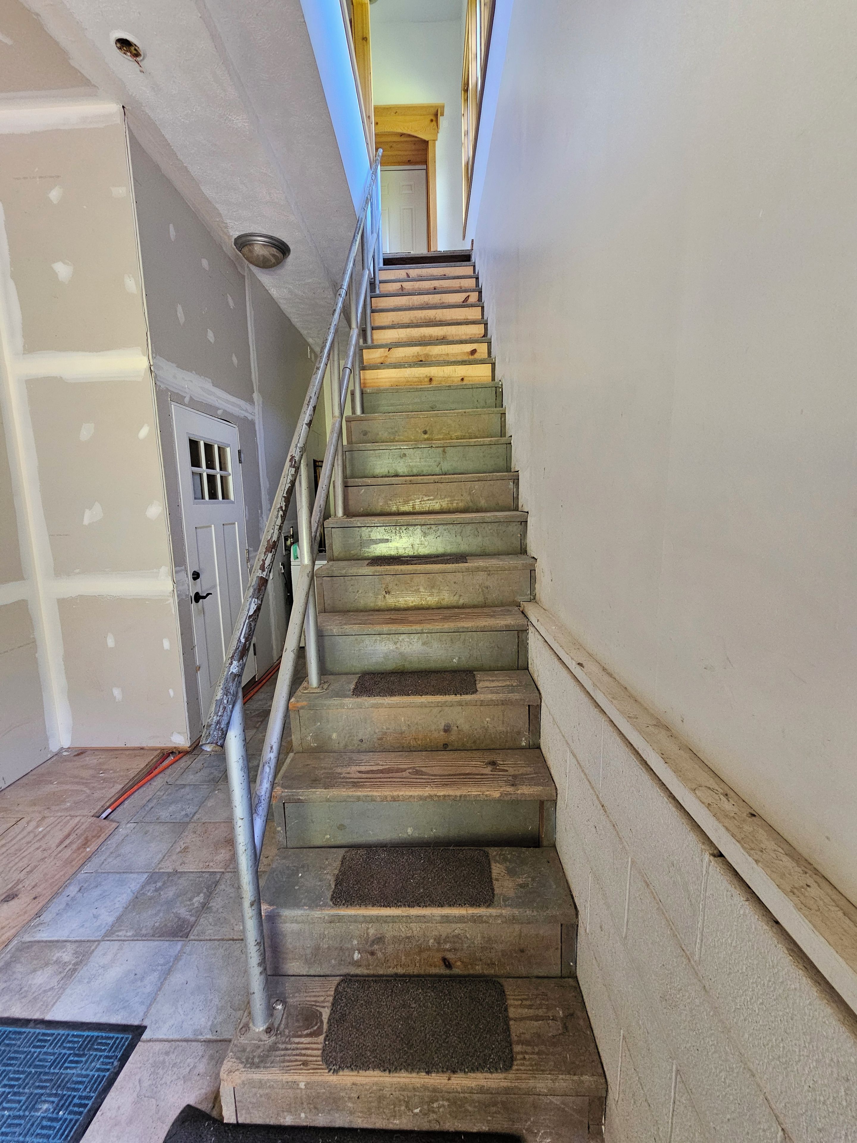 A staircase with wooden steps and metal railings, leading to an upper floor.