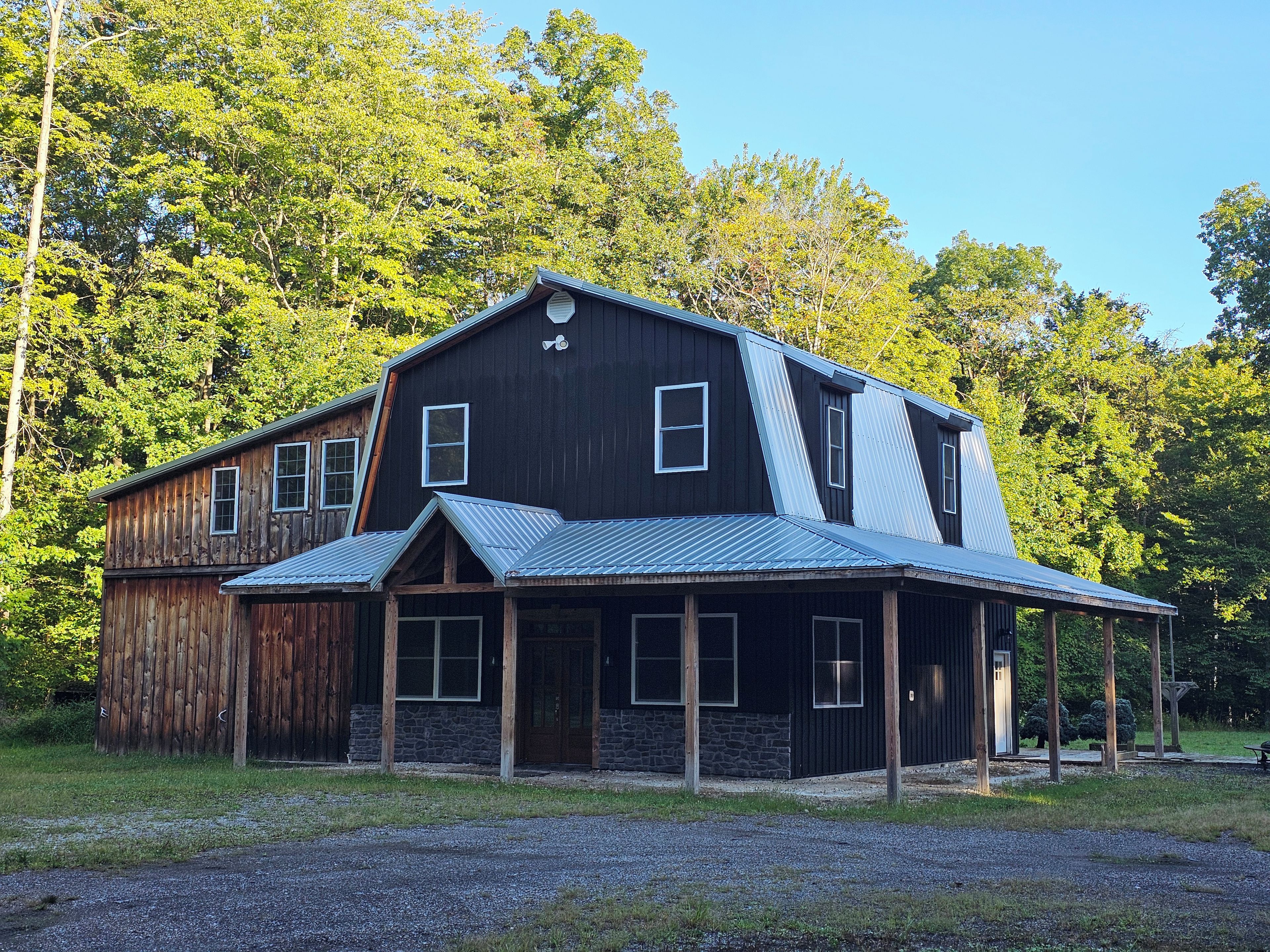 A two-story wooden building with a metal roof, surrounded by trees.