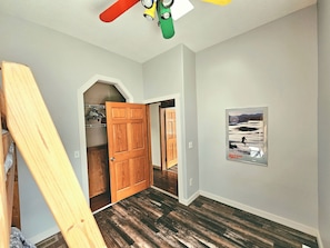 Una habitación con puerta de madera, un cartel en la pared y un ventilador de techo.