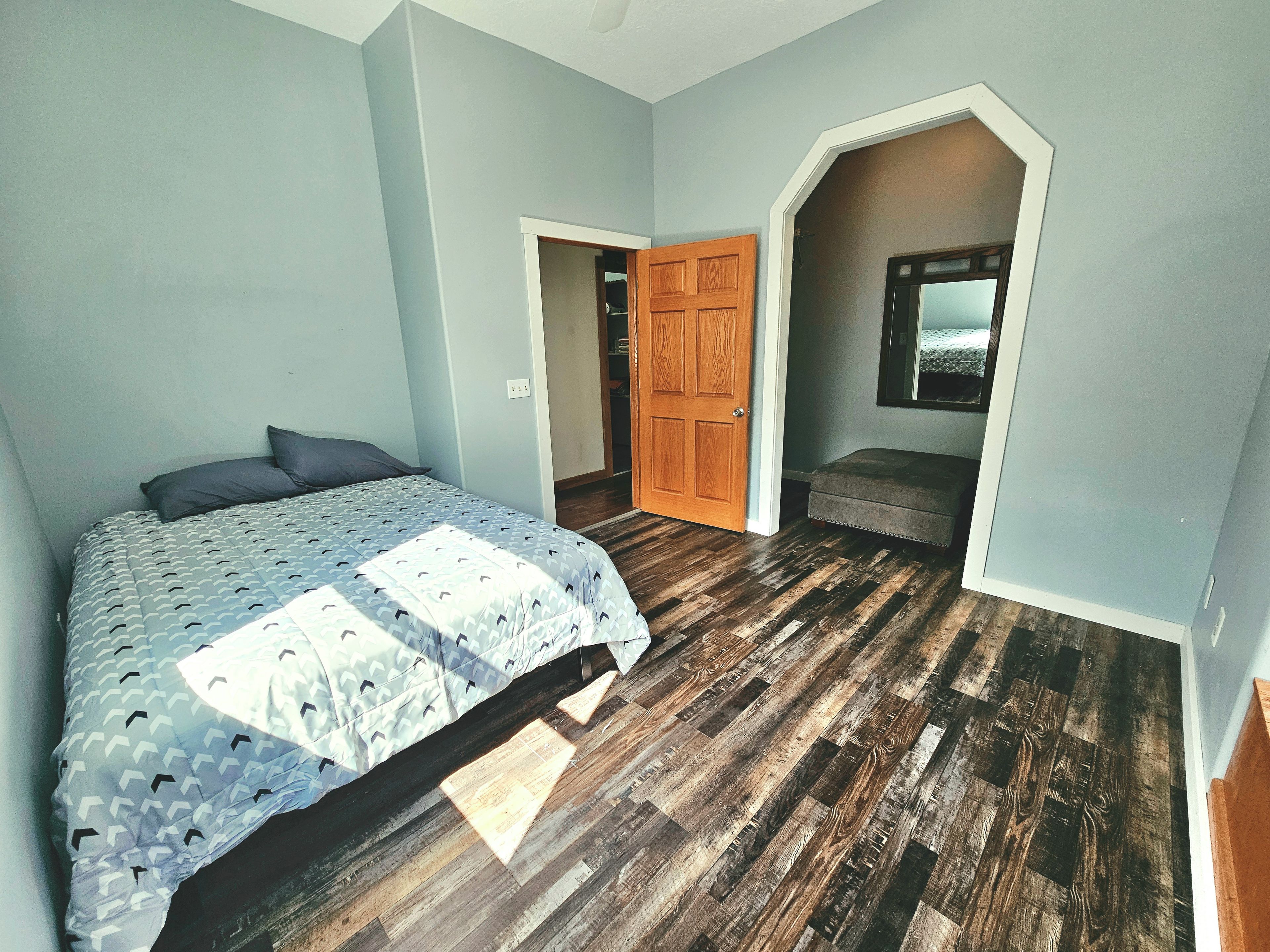 Ein Schlafzimmer mit einem Bett, einer Holztür und einer Bank.