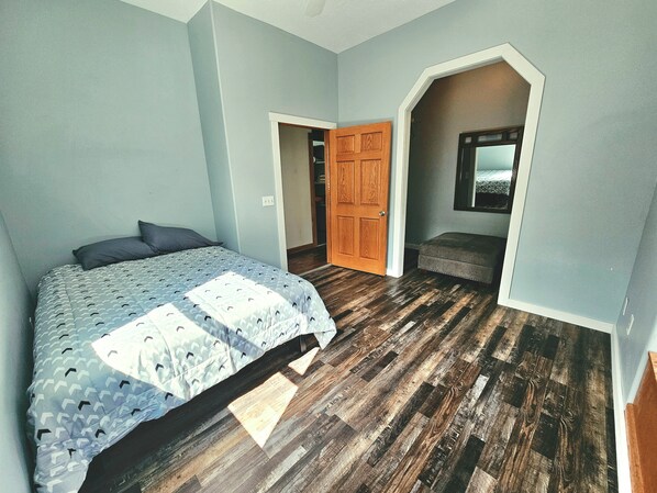 Un dormitorio con cama, una puerta de madera y un banco.