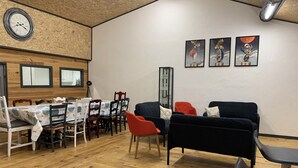 Un comedor con una mesa y sillas de madera, un sofá negro y un reloj en la pared.