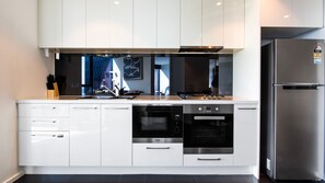 A modern kitchen with white cabinetry, a stainless steel refrigerator, and built-in appliances including a microwave, oven, and stove. - Cloud 45 City Views in Southbank (Southbank)