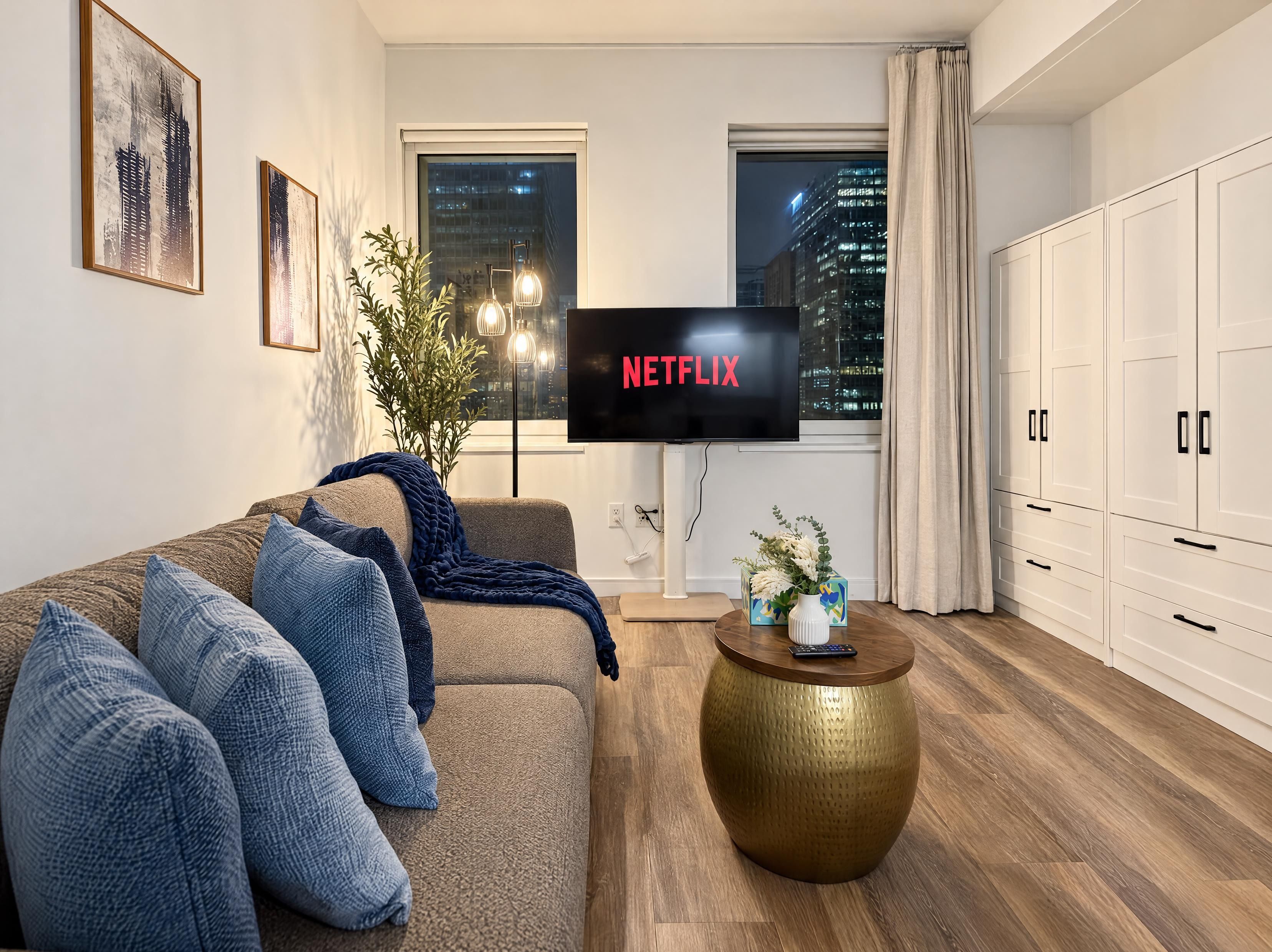 Een moderne woonkamer met een bank, een salontafel en een tv waarop 'NETFLIX' wordt weergegeven.