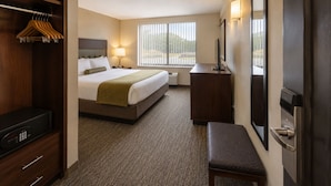 A hotel room with a bed, bedside table, lamp, TV, and a wardrobe. - Midtown Highrise Condo Near Times Square (New York)