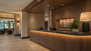 A reception desk with a stone accent wall, a potted plant, and a lamp. - Midtown Highrise Condo Near Times Square (New York)