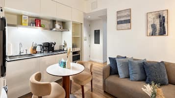A modern kitchen with a dining area, a sofa, and artwork on the walls.