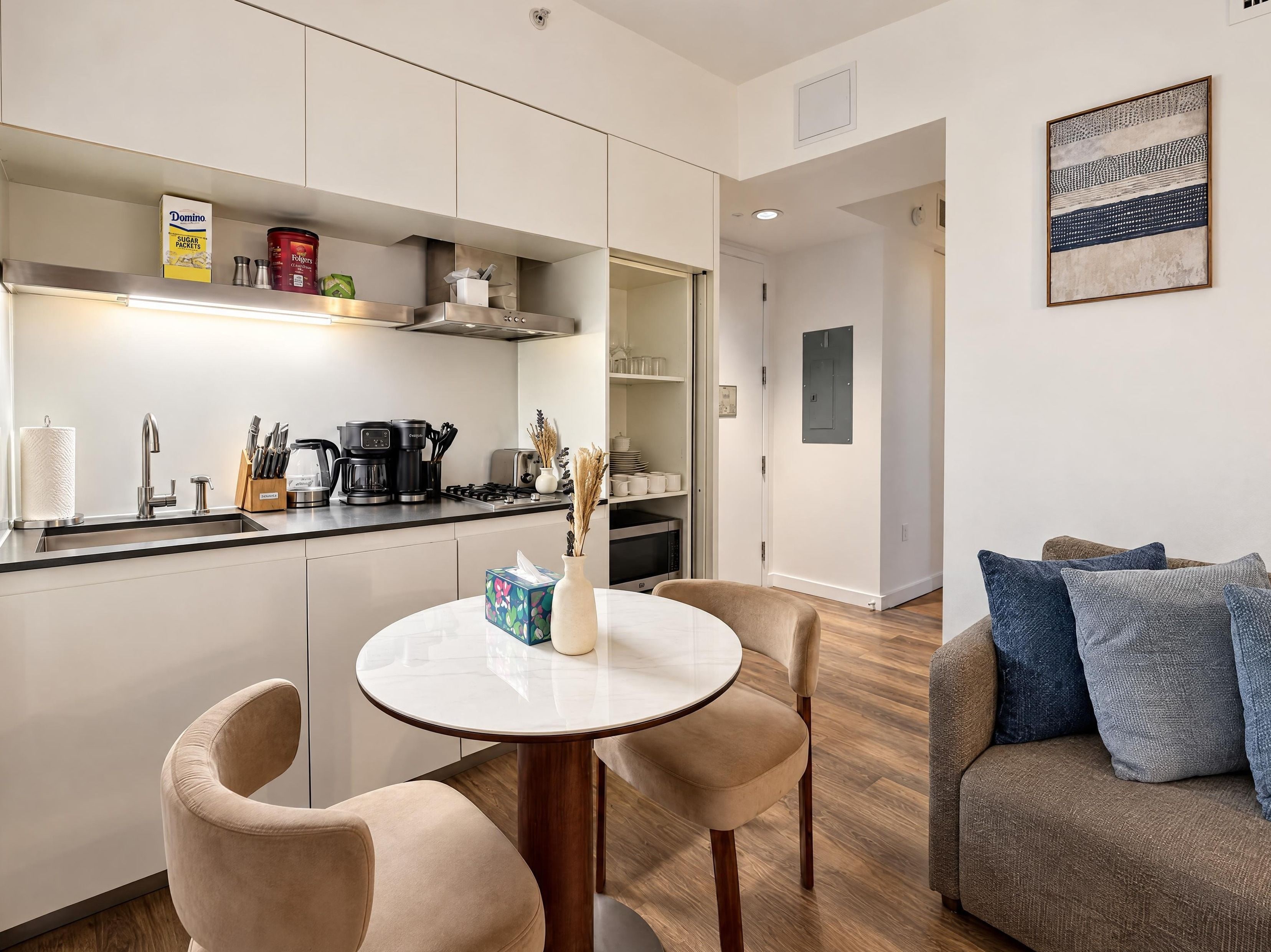 Een moderne keuken met een eethoek, inclusief een ronde tafel met stoelen, een koffiezetapparaat en een broodrooster.