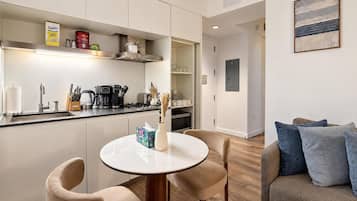Een moderne keuken met een eethoek, inclusief een ronde tafel met stoelen, een koffiezetapparaat en een broodrooster.