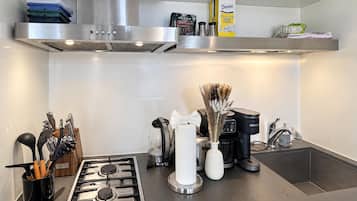 A modern kitchen with a stainless steel range hood, a coffee maker, and a box of Domino sugar packets.