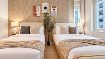 A hotel room with two beds, a textured wall, and artwork.