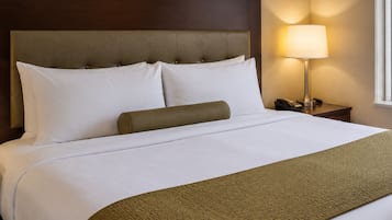 Ein Hotelzimmer mit Bett, Kopfteil, Nachttischlampe und Nachtschränkchen.